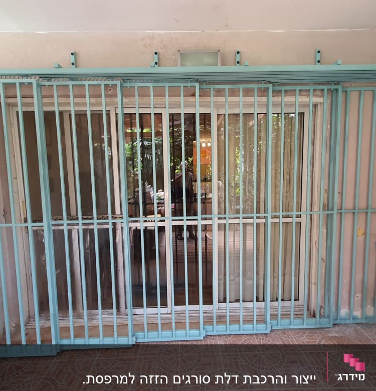 סורגים מתכתיים בצבע תכלת על חלון זכוכית